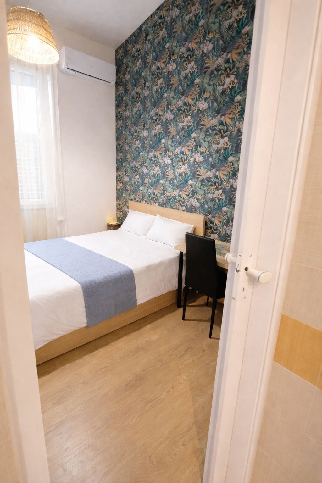 A bedroom with a bed, a desk, and a chair.