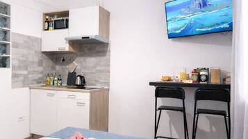 Una habitación de hotel moderna con cama, escritorio, televisor y kitchenette.