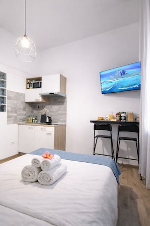 Una habitación de hotel moderna con cama, escritorio, televisor y kitchenette.