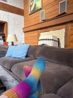 A living room with a brown sofa, a lamp, and a painting on the wall.