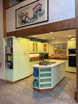 A kitchen with light green cabinets, a central island, and a patterned floor.