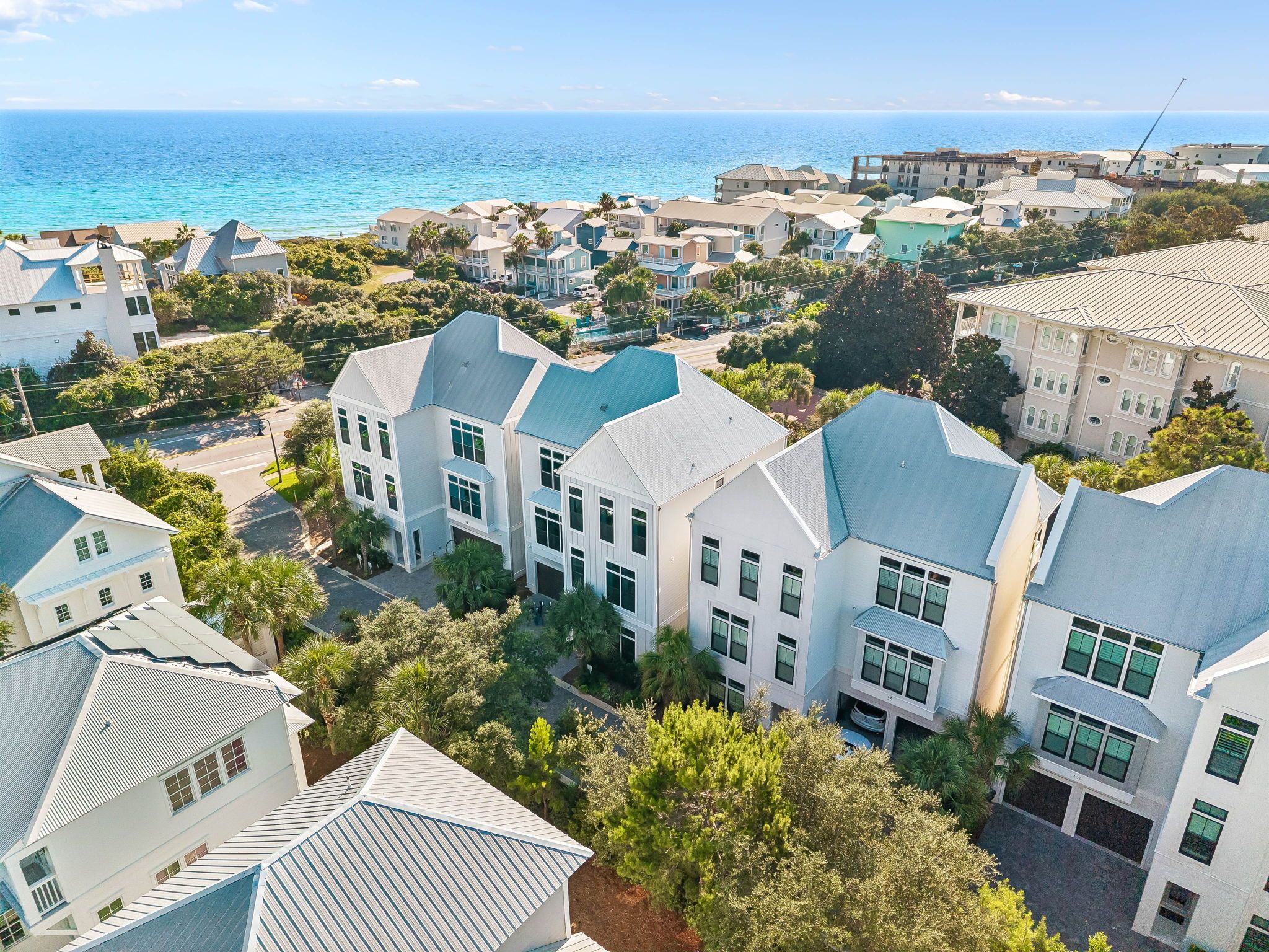 Aerial view showcasing the property's prime coastal location, nestled among lush greenery with stunning turquoise waters just steps away from this charming beach community.
