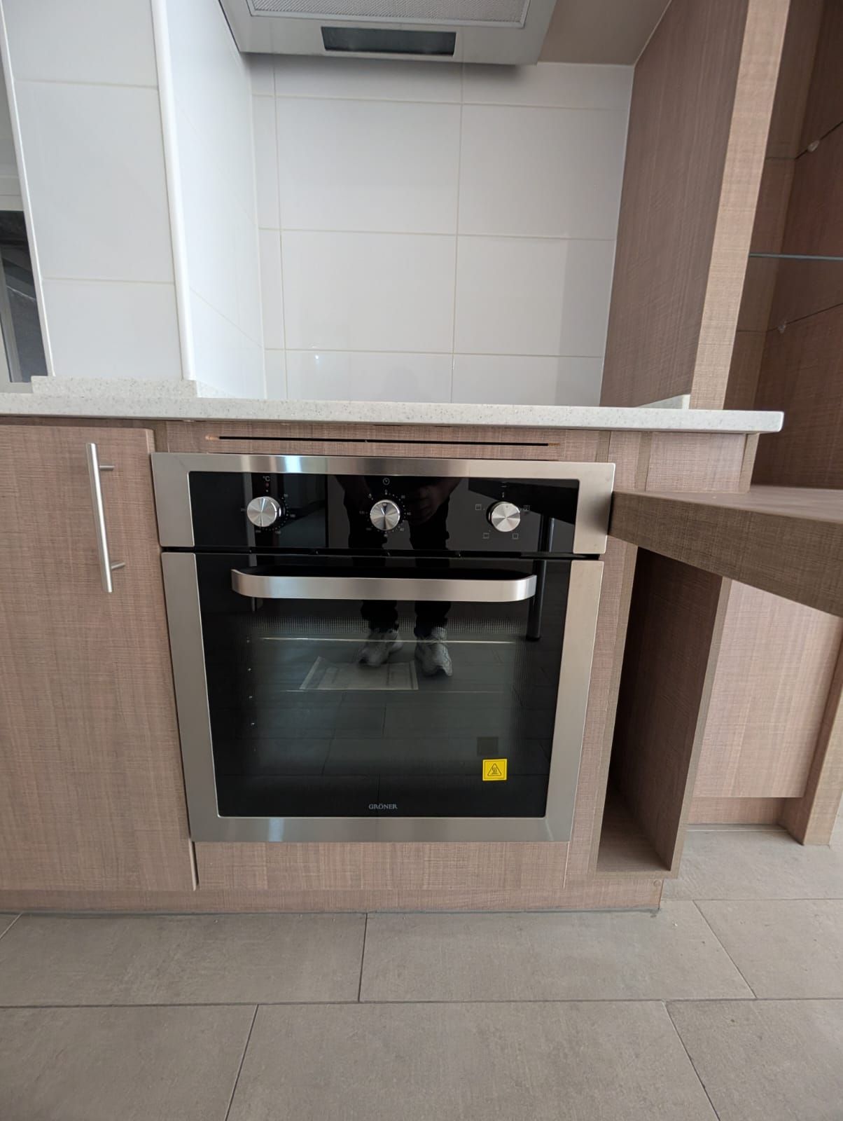 Cozinha com forno embutido, bancada e armários de madeira.