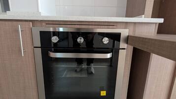 Cozinha com forno embutido, bancada e armários de madeira.
