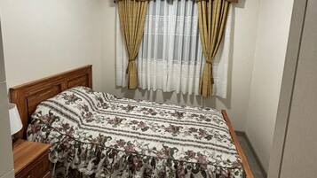 A bedroom with a bed, curtains, a nightstand, and a ceiling light.