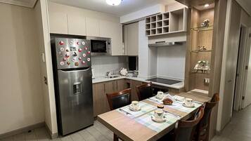 Una cucina moderna con forno a microonde integrato, frigorifero in acciaio inossidabile e zona pranzo con tavolo apparecchiato per quattro persone.