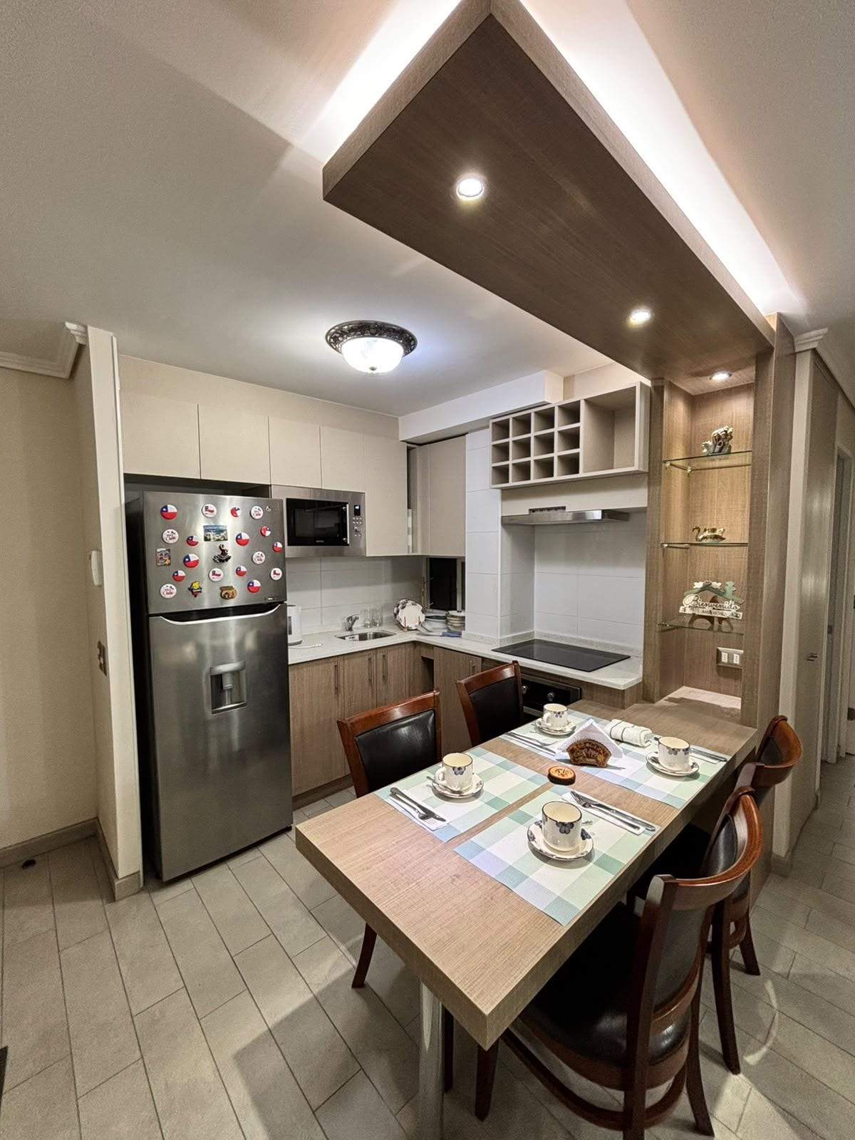 A modern kitchen with a built-in refrigerator, microwave, and a dining area with a table set for two.