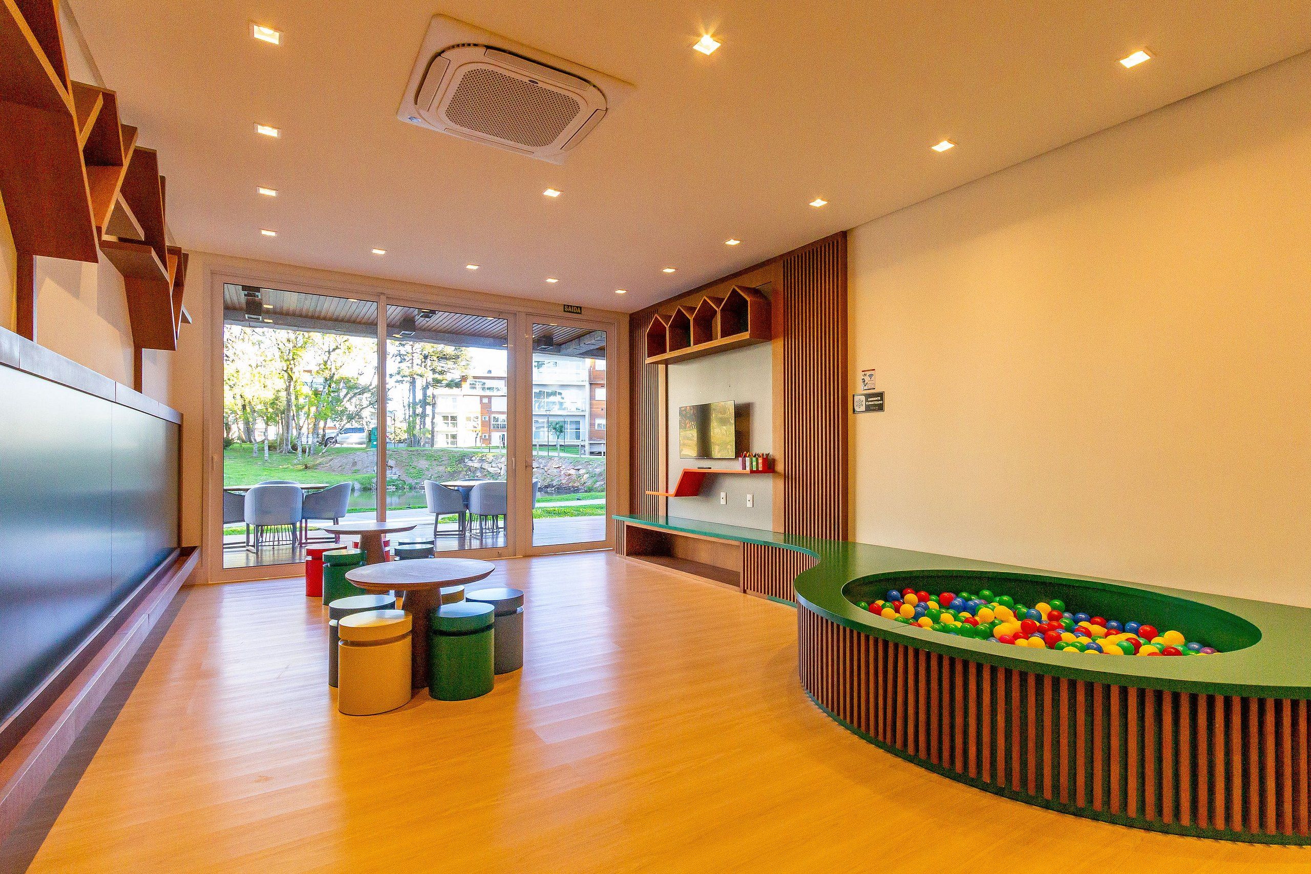 A modern indoor pool area with a green pool table, seating, and a view of the outdoors.