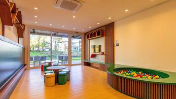 A modern indoor pool area with a green pool table, seating, and a view of the outdoors.
