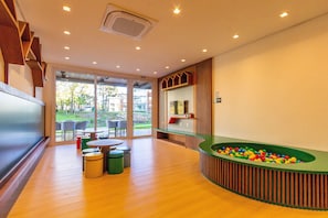 A modern indoor pool area with a green pool table, seating, and a view of the outdoors. - Vêneto Baldanho 101 (Gramado)
