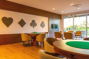 Quarto com mesa de bilhar, cadeiras e decoração nas paredes, incluindo corações e cartas de baralho.