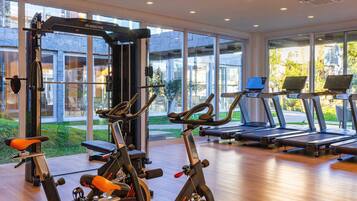 A gym with exercise equipment, large windows, and a view of the outdoors.