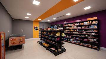 A grocery store with shelves stocked with various products, a freezer section, and a home market sign.