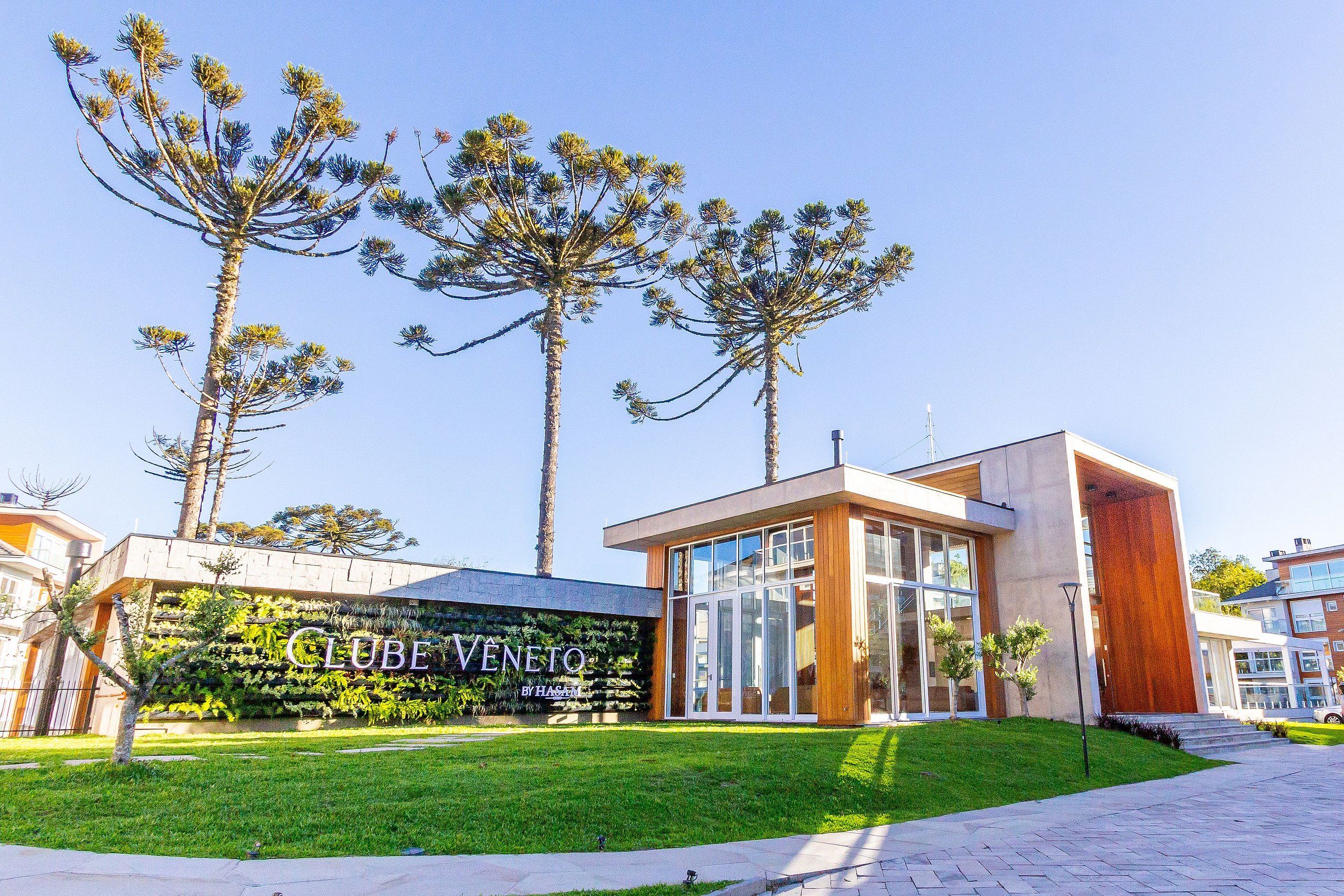 A modern building with a glass facade and a sign that reads 'CLUBE VENTO BY HASAM'.