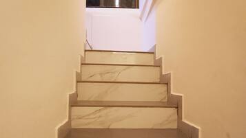 A marble staircase leading to a landing with a window.
