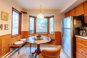 A kitchen with a wooden interior, a dining table with chairs, a refrigerator, and a coffee maker. - Urban cabin near chocolate lake with sauna (Halifax)