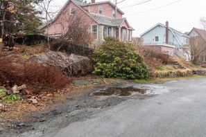 A residential street with houses, a wet road, and a bush. - Urban cabin near chocolate lake with sauna (Halifax)