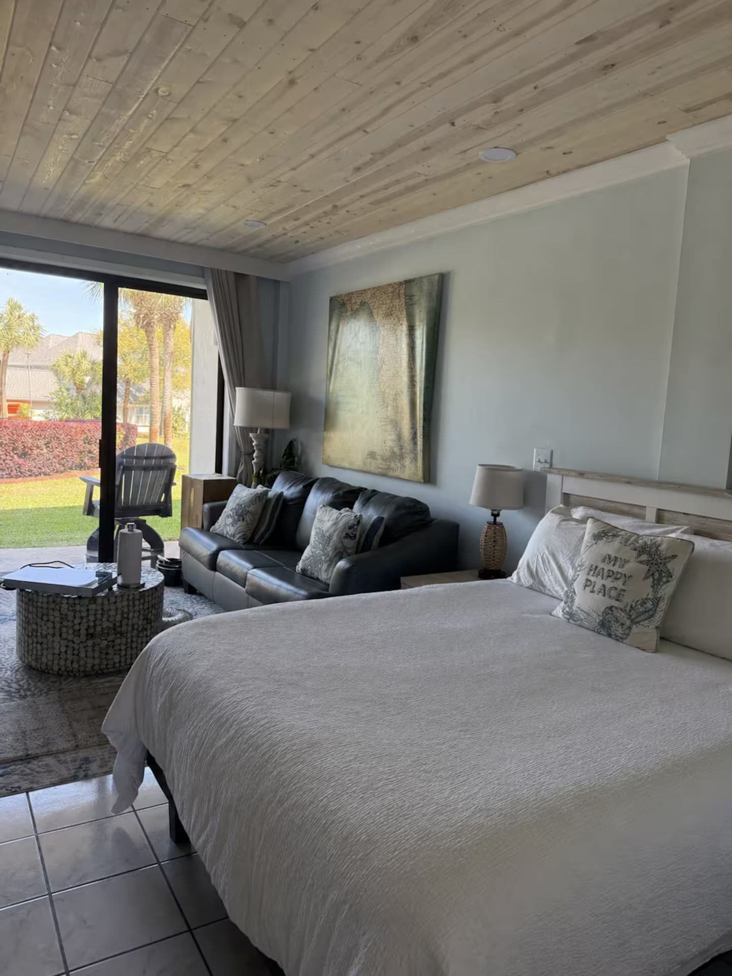 Un dormitorio con una cama grande, un sofá, una silla y una mesita.