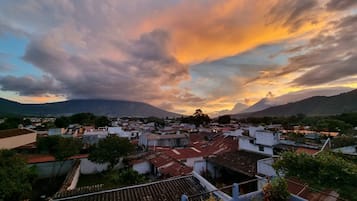 Bairro residencial com casas, uma montanha ao fundo e céu ao pôr do sol.