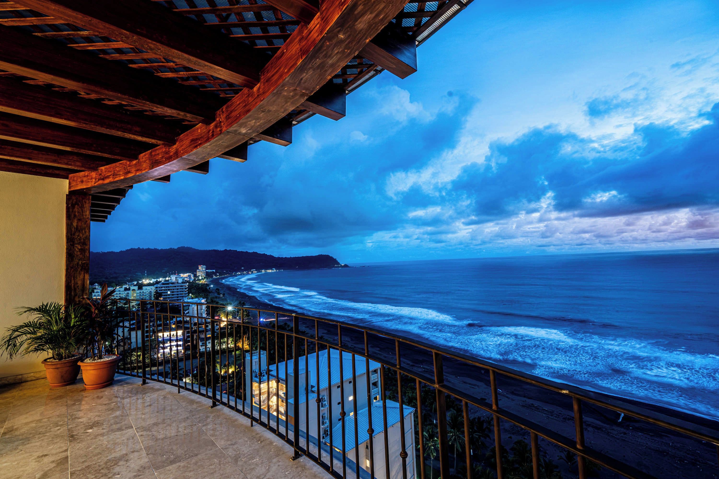 A balcony with a view of the ocean and a cityscape.