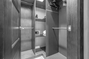 Ein moderner, gut beleuchteter begehbarer Kleiderschrank mit Holztüren und einem Metallgriff.