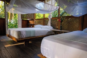 A room with two beds, a wooden floor, and a canopy bed with a mosquito net. - Luzul Ecohotel (Arusi)