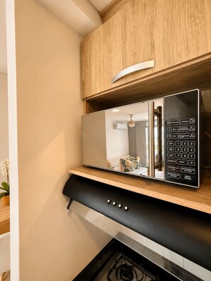 A modern kitchen with a built-in microwave, a wooden cabinet above, and a black range hood below. - Sienna Grove | Terrace, Caribbean Views & Pool (Cartagena)