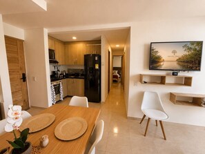 A modern kitchen with wooden cabinets, a black refrigerator, and a dining area with a table and chairs. - Sienna Grove | Terrace, Caribbean Views & Pool (Cartagena)