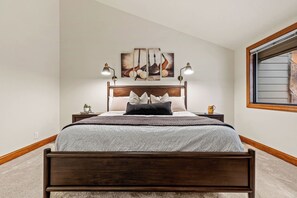Een slaapkamer met een houten bed, een hoofdbord, een nachtkastje, een lamp en een raam.