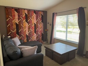 A living room with a dark sofa, a coffee table, and a large patterned wall hanging. - SunDance Film Festival Travelers: Cosy 2-bedroom condo  in adorable Broomfield (Broomfield)