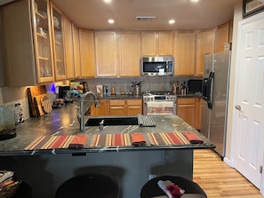A modern kitchen with wooden cabinets, stainless steel appliances, and a central island with a sink. - SunDance Film Festival Travelers: Cosy 2-bedroom condo  in adorable Broomfield (Broomfield)