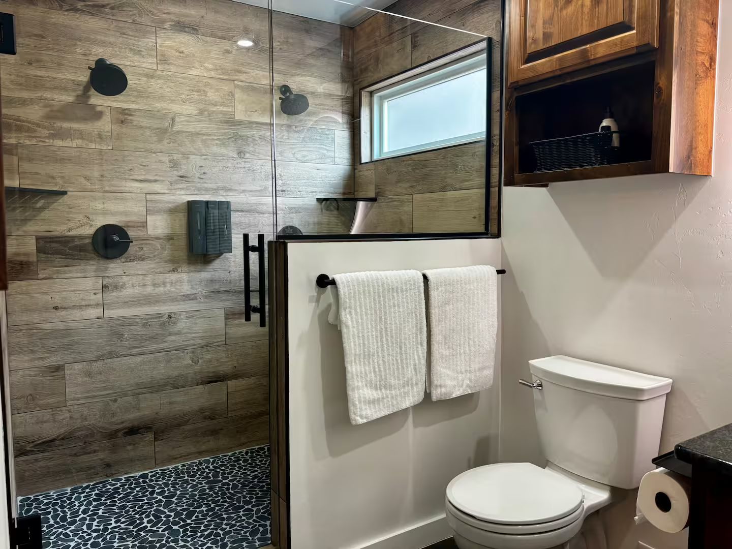 A modern bathroom with a shower, toilet, and a mirror above the sink.