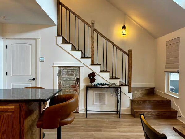 Un intérieur moderne avec un escalier en bois, un coin repas comprenant une table et des chaises, et une cheminée.