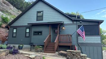 Een huis met twee verdiepingen, een voortuin, een stenen muur en een Amerikaanse vlag.