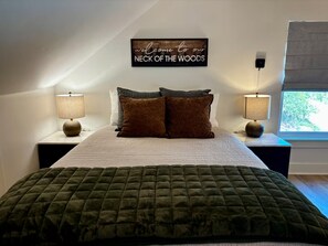 Une chambre à coucher avec un lit, deux tables de chevet, deux lampes, un tableau ou une décoration au-dessus du lit et une fenêtre.