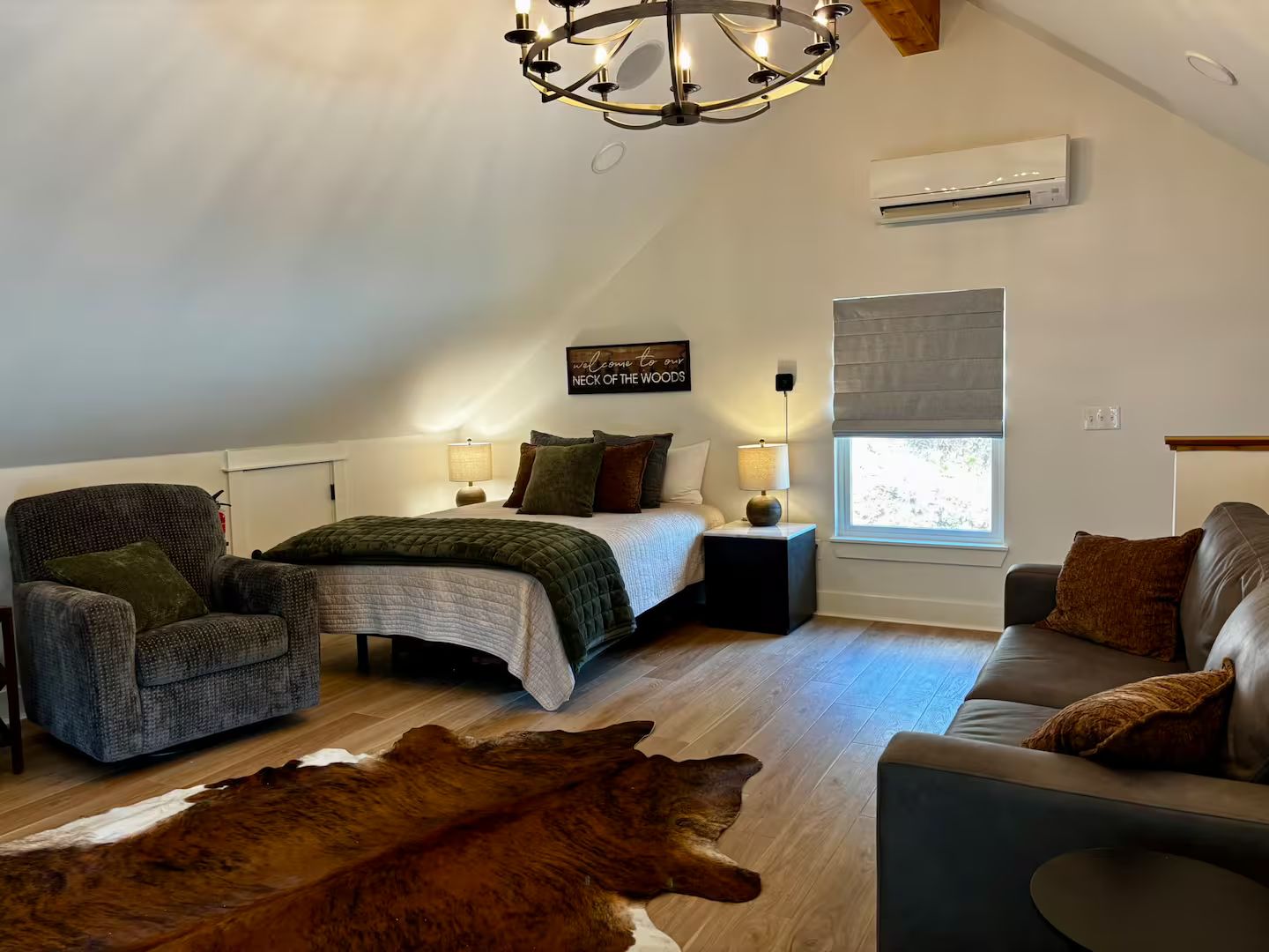 Een gezellige slaapkamer met een bed, een fauteuil, een bank, een vloerkleed en een kroonluchter.