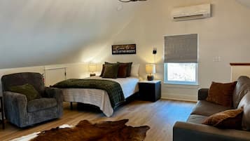 Een gezellige slaapkamer met een bed, een fauteuil, een bank, een vloerkleed en een kroonluchter.