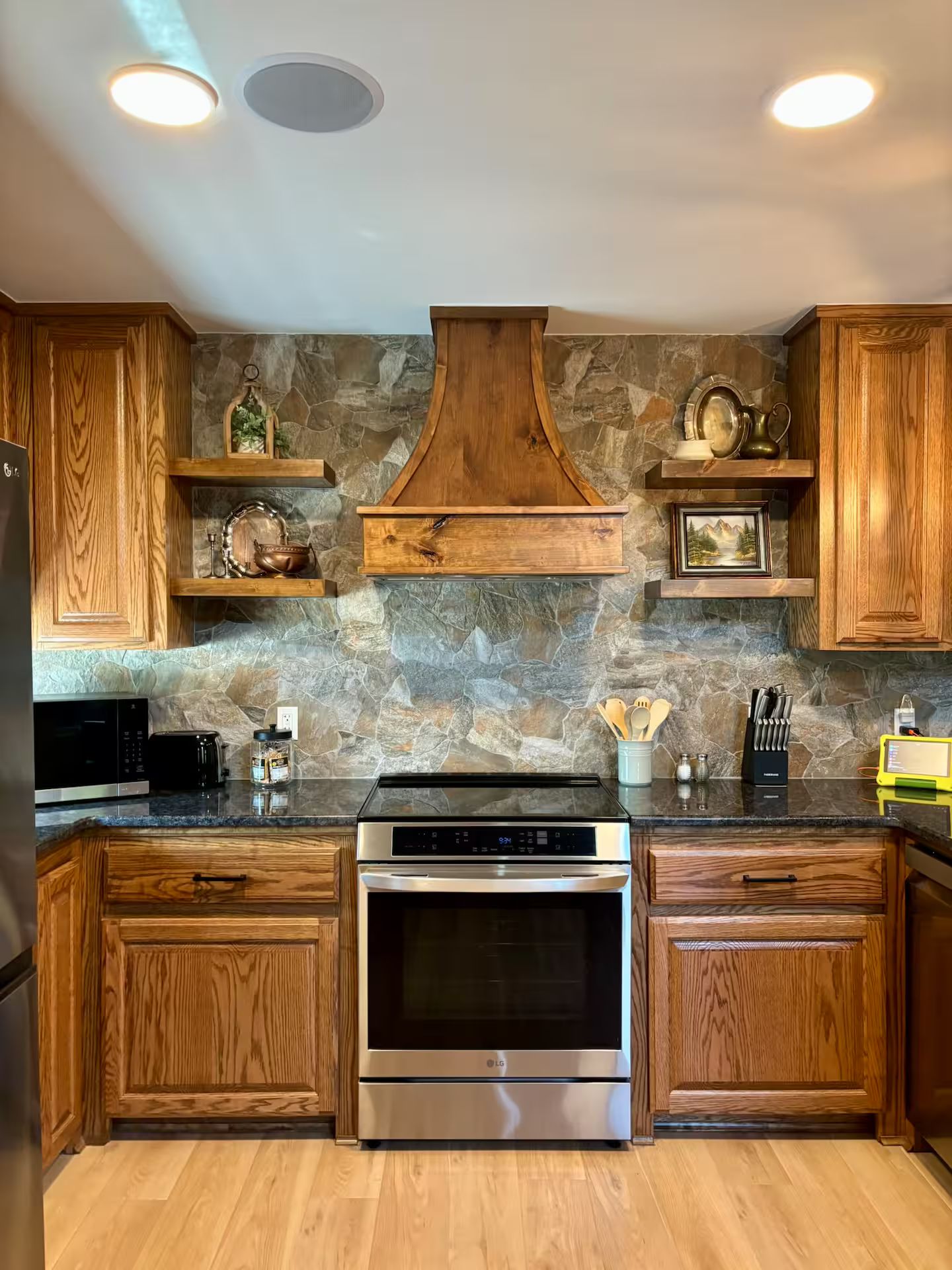A kitchen with wooden cabinets, a stone backsplash, a stainless steel oven, and a built-in microwave.