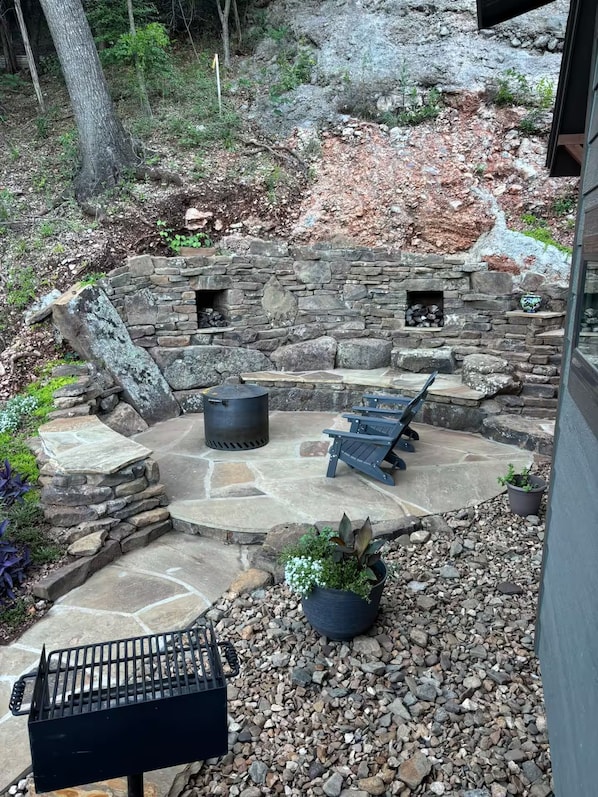 A stone patio with a grill, seating, and planters.