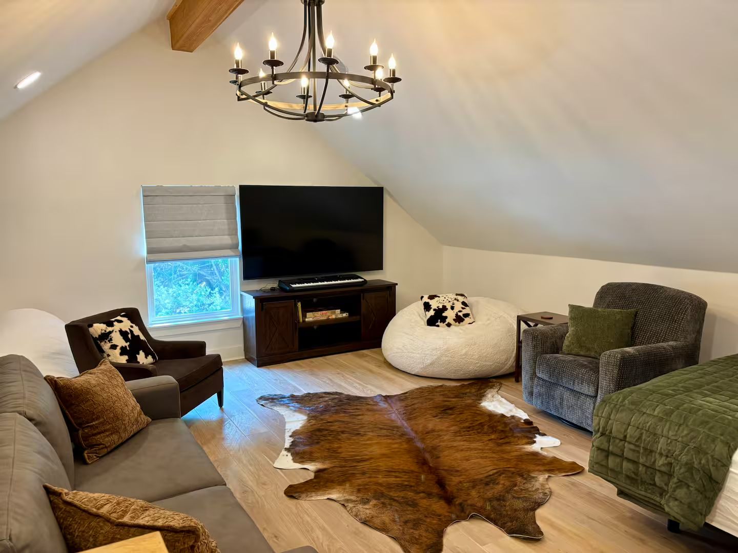 Een moderne loft-woonkamer met een grote flatscreen-tv, een leren bank, een plufkussen en een kroonluchter.