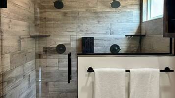 A modern bathroom with a glass shower enclosure, wooden wall tiles, and a white toilet.