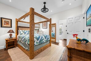 A four-poster bed with a tropical leaf pattern, a wooden nightstand, a lamp, and a framed picture on the wall. - Indiana Jones & Jungle Cruise • Genuine Disney Décor • Secret Bookcase • Pool (Clermont)
