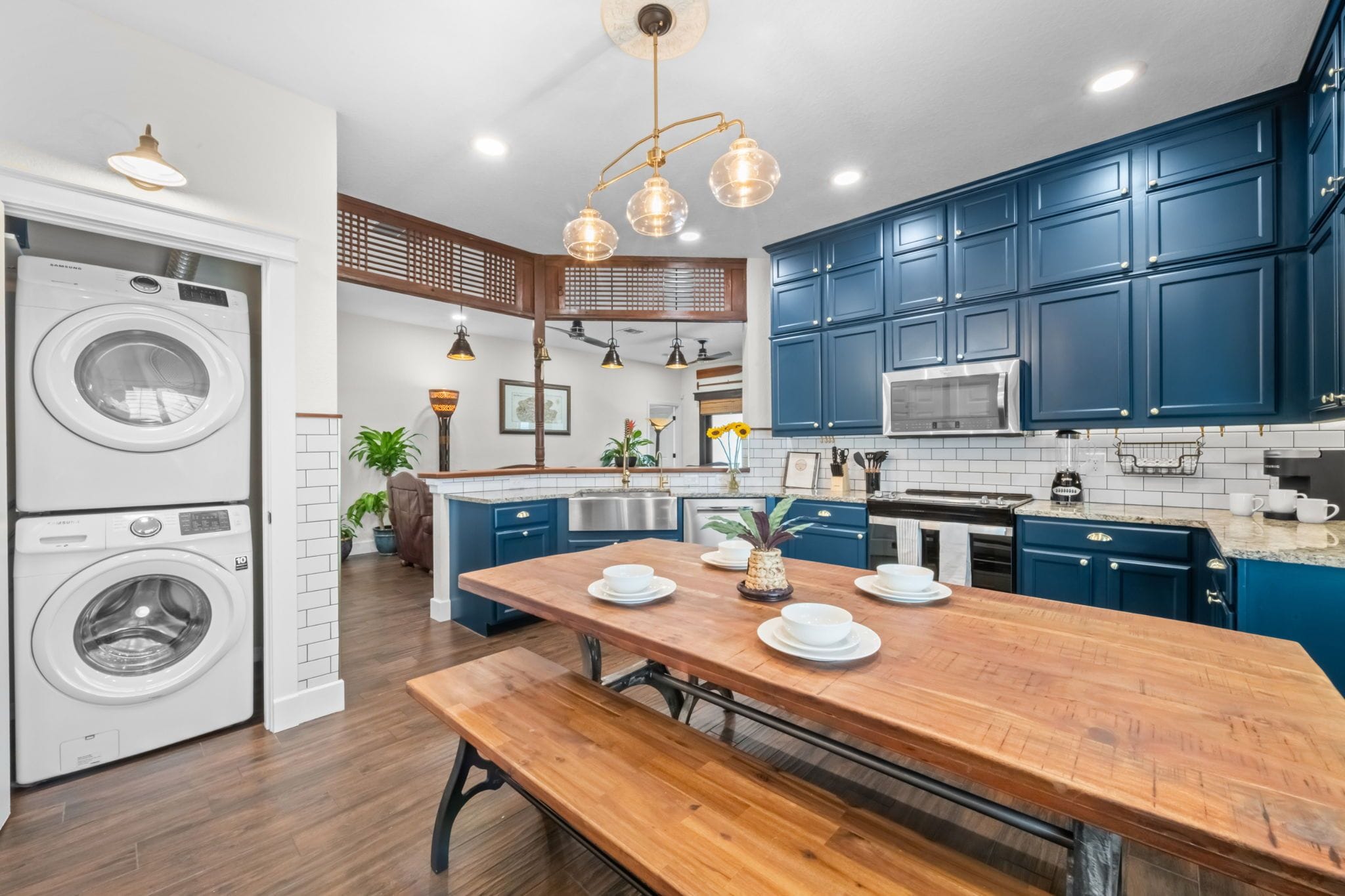 A modern kitchen with blue cabinets, a wooden dining table, and built-in appliances.