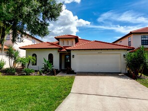 A residential house with a red-tiled roof, a garage, and a well-maintained lawn. - Indiana Jones & Jungle Cruise • Genuine Disney Décor • Secret Bookcase • Pool (Clermont)