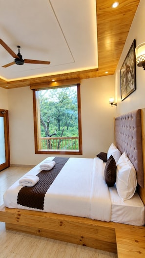 Un dormitorio con cama, ventilador de techo, ventana con vistas y lámpara de pared.