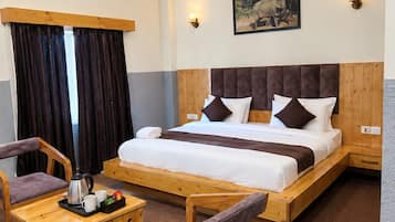 A hotel room with a wooden ceiling, a bed with a headboard, two bedside tables, a coffee table, and two chairs.