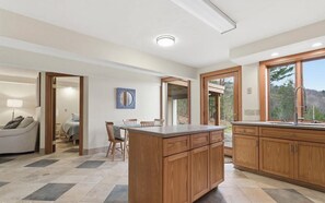 A modern kitchen with wooden cabinets, a central island, and a view of the outdoors.