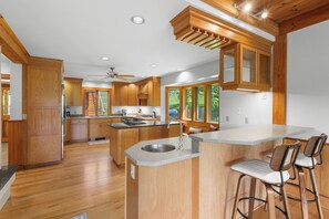 A modern kitchen with wooden cabinetry, a central island with a sink, and a bar area with stools.