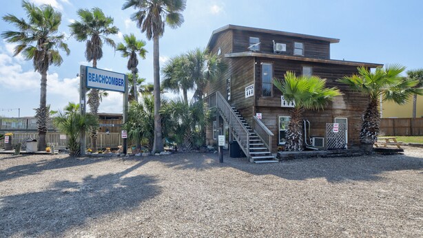 Ein Holzgebäude mit einem Schild, auf dem 'BEACHCOMBER' steht, und einer Treppe, die zum Eingang führt.