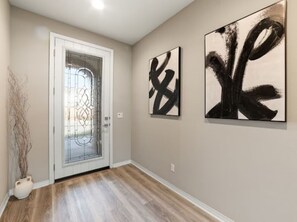 A hallway with a door, abstract art on the wall, and a potted plant. - South-Facing La Quinta Pool Home with Stunning Mountain & Sunset Views (La Quinta)